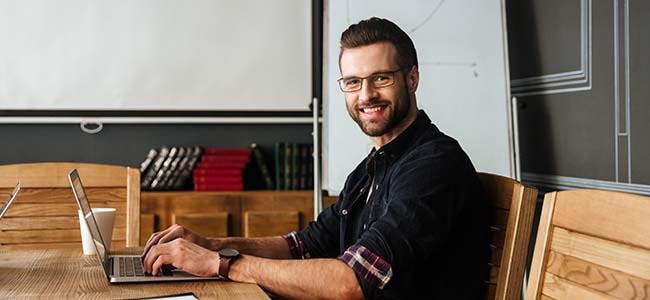 upskilling Coders Lab Smiling man with laptop in a classroom